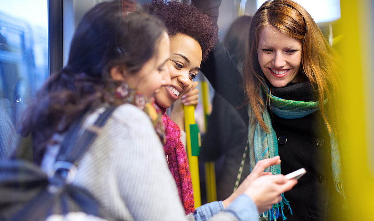 Women on public transport and using their mobile phone to learn how to say the days of the week in Portuguese.