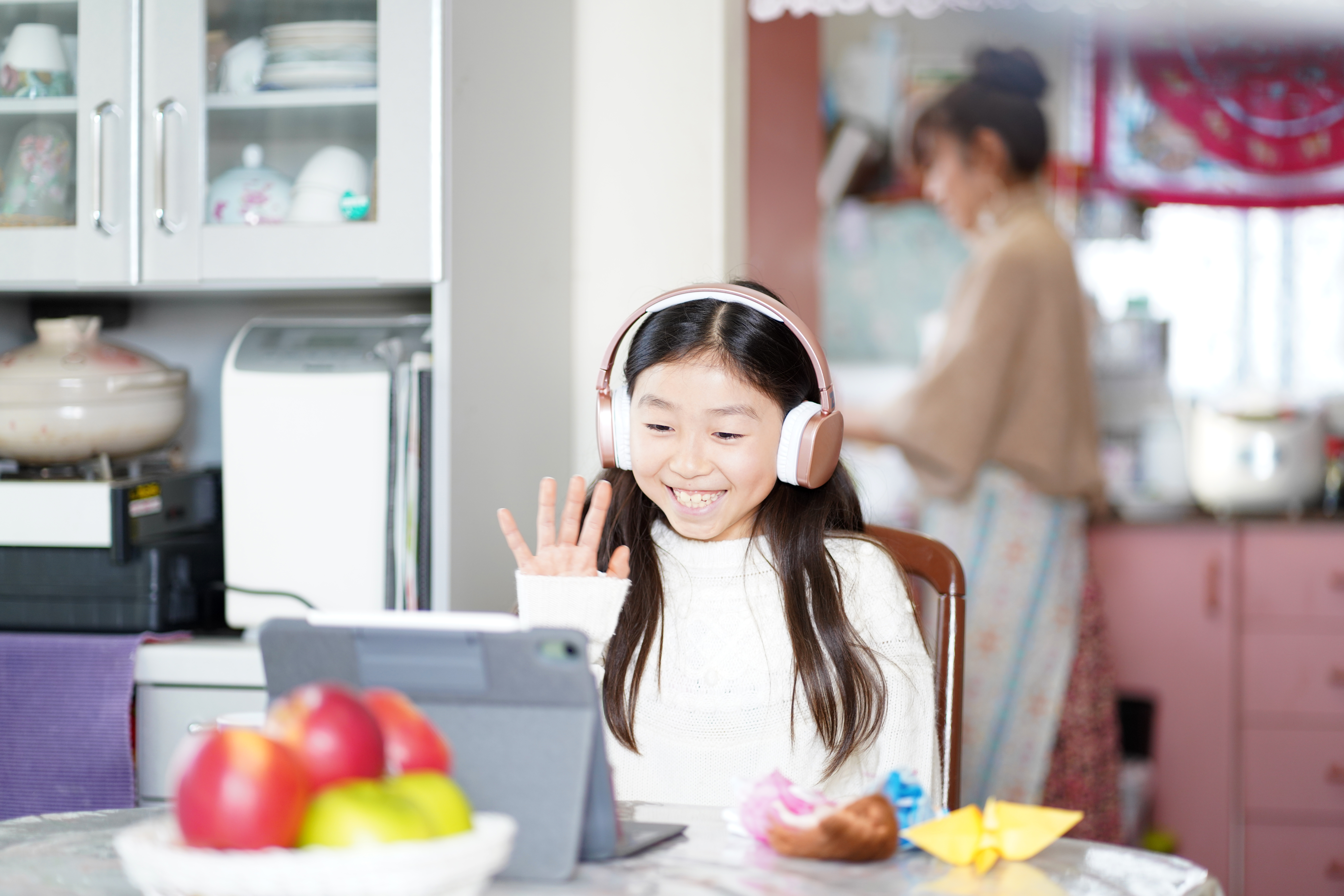 Smiling young girl wearing headphones attending an online language learning session at home

