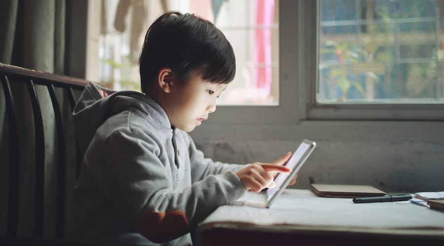 Young boy using a tablet to attend an online French class at home
