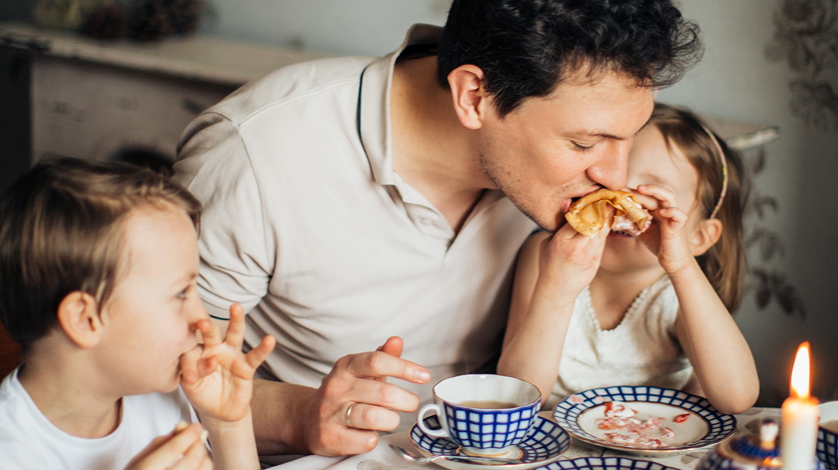 Children eating breakfast with their father in Italian.