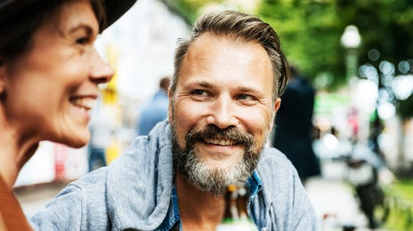 Two people enjoying a relaxed outdoor café conversation, ideal for practicing conversational Danish in a friendly setting.
