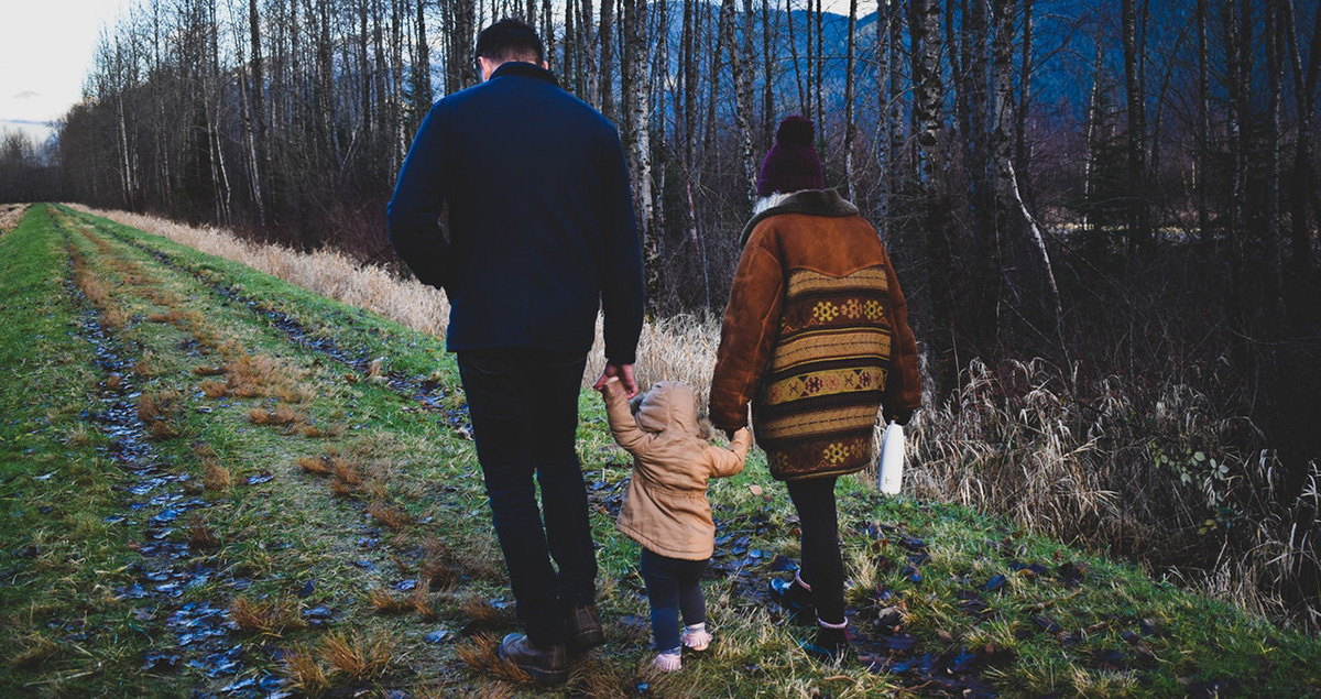 Little boy walks with his family members in German forest.