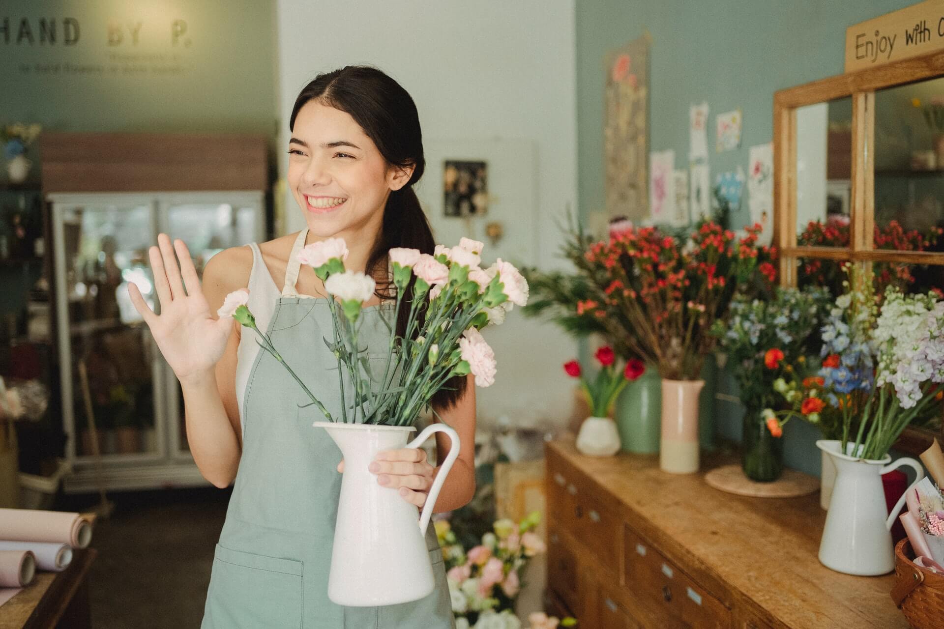 Florist holding a vase of flowers and learning how to say hello in Spanish