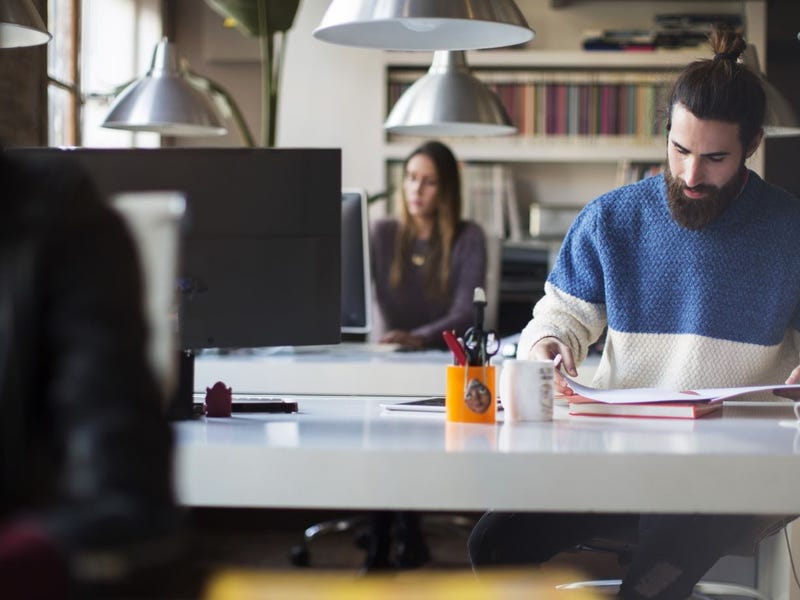 A man focused on reading documents at a modern, shared workspace.