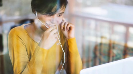 Woman taking a private English class online using a laptop and headset at home