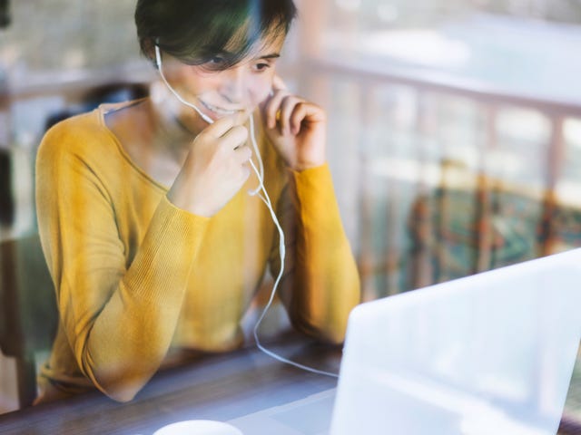 Woman taking a private English class online using a laptop and headset at home