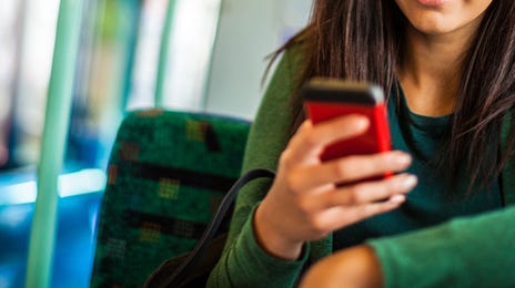 Young woman learning Croatian online using her smartphone while riding public transportation