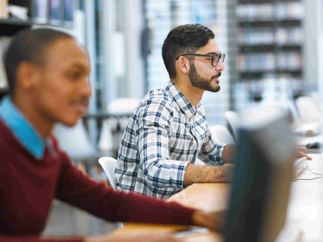 Students working on desktop computers in a modern library.