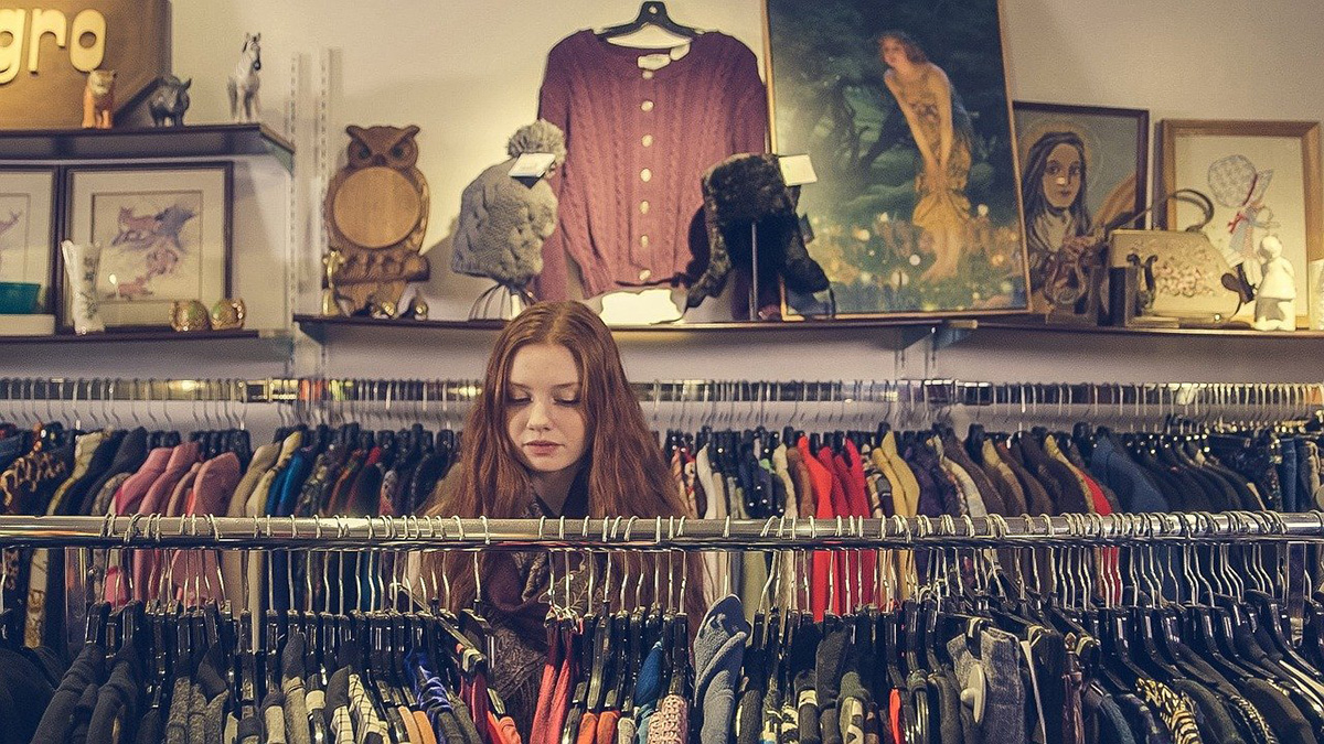 Young woman searching for clothes in a secondhand fashion store in France.