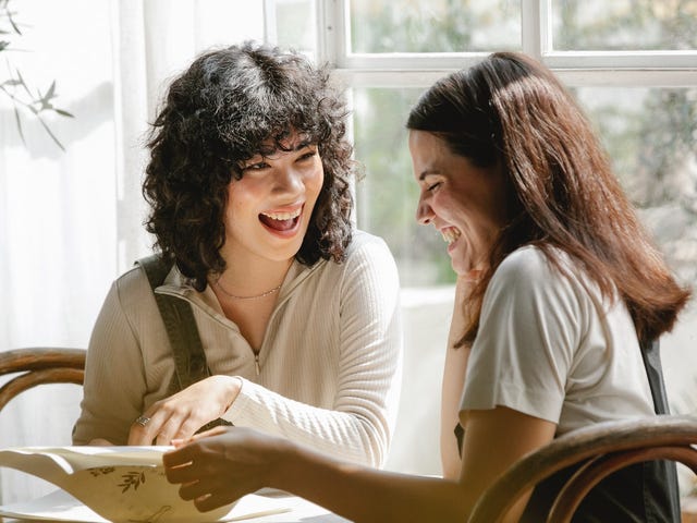 Examples of mentoring in the workplace with two happy diverse work friends smiling and learning.