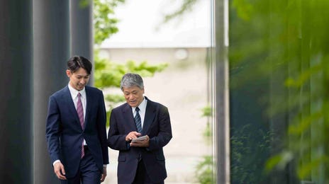 Two professionals walking and discussing results on a tablet, representing Berlitz Speak Test for business English communication assessment.