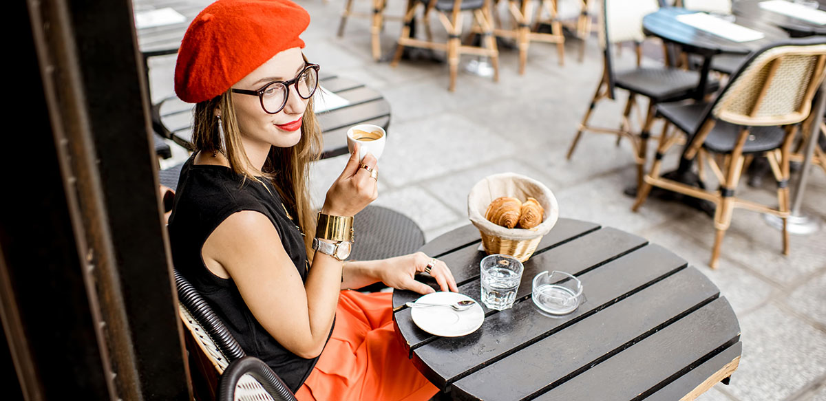 Woman having a café and a croissant at a Parisian café terrace.