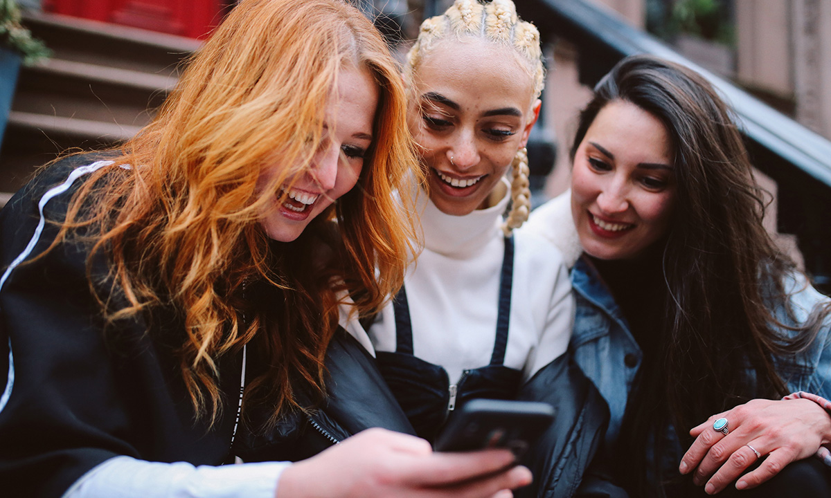 Friends search how to say hello in Portuguese on their phone.