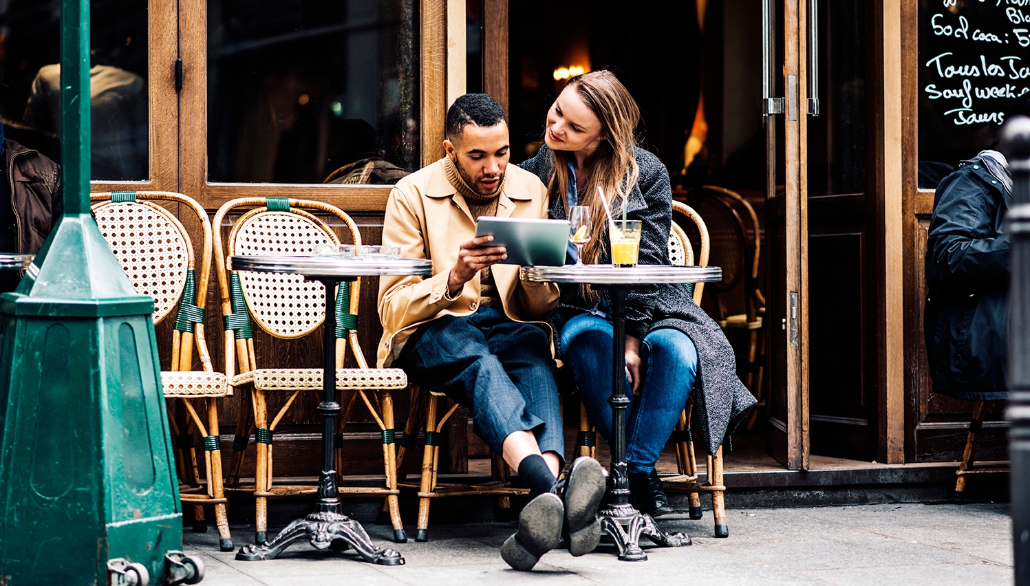 Couple practicing how the tell the time in French at a cafe.