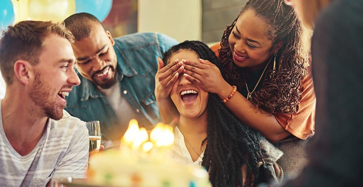 Friends surprise their friend with a party and cake showcasing surprise German words for emotions.