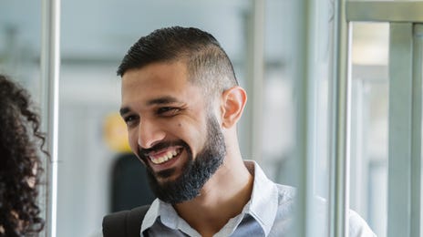 Smiling man talking with a fellow passenger on public transit, symbolizing real-world Urdu language practice