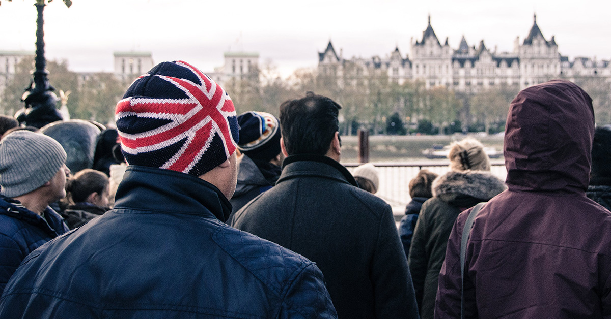 An American tourist wearing a British flag beanie, admiring a building in England.