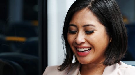 Smiling woman on public transport studying advanced English courses on her smartphone