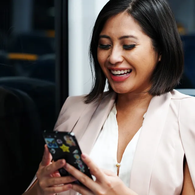 Smiling woman on public transport studying advanced English courses on her smartphone