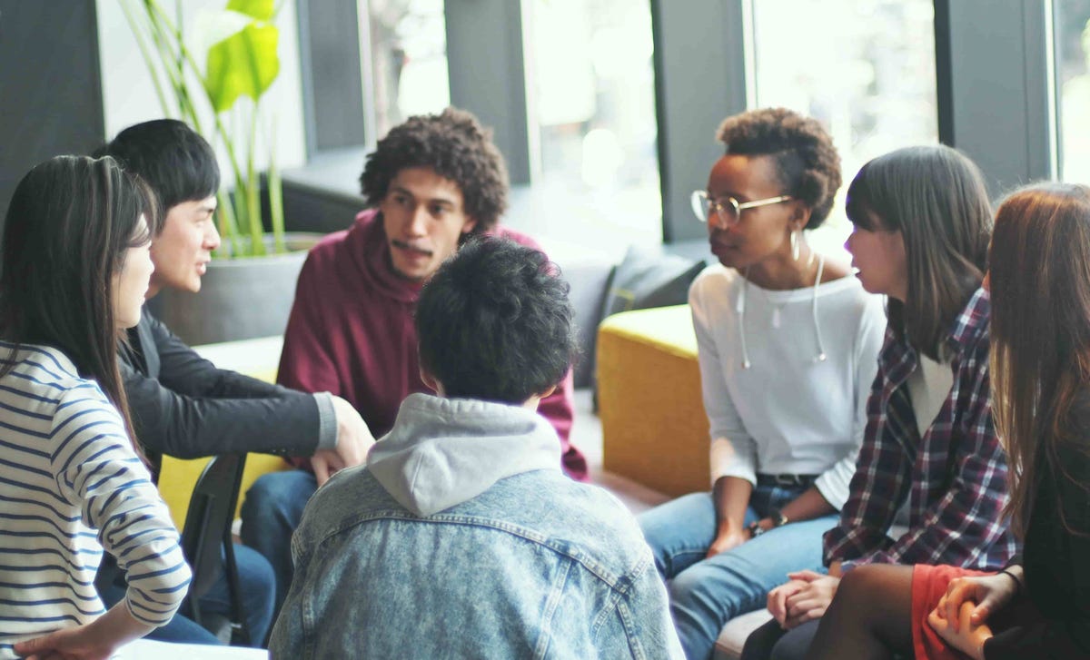 A diverse group of students in a lively discussion setting, representing collaborative learning environments available through online German classes.