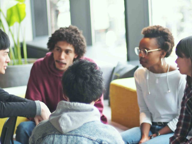 A diverse group of students in a lively discussion setting, representing collaborative learning environments available through online German classes.