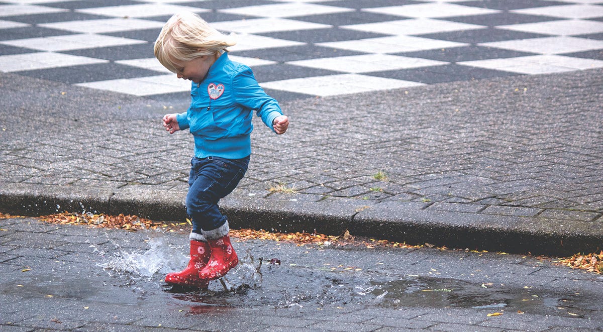 Young child jumping in puddles in Spanish.