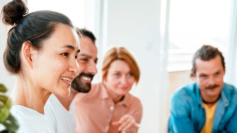 Smiling group of people in a classroom or training setting engaged in a discussion about building a German teaching career.