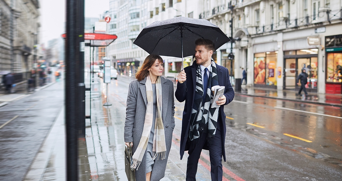 Woman tells man you're very welcome in Spanish as he holds umbrella for her.