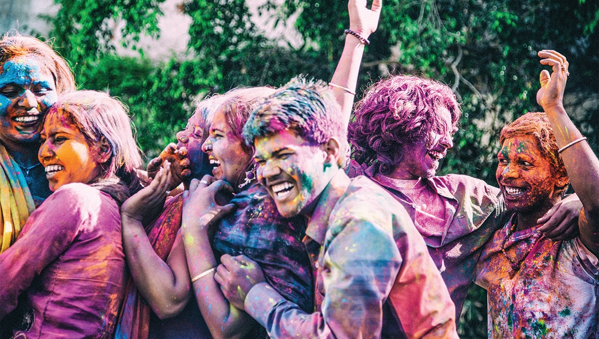 színes festékkel összefestett emberek ölelkeznek és nevetnek