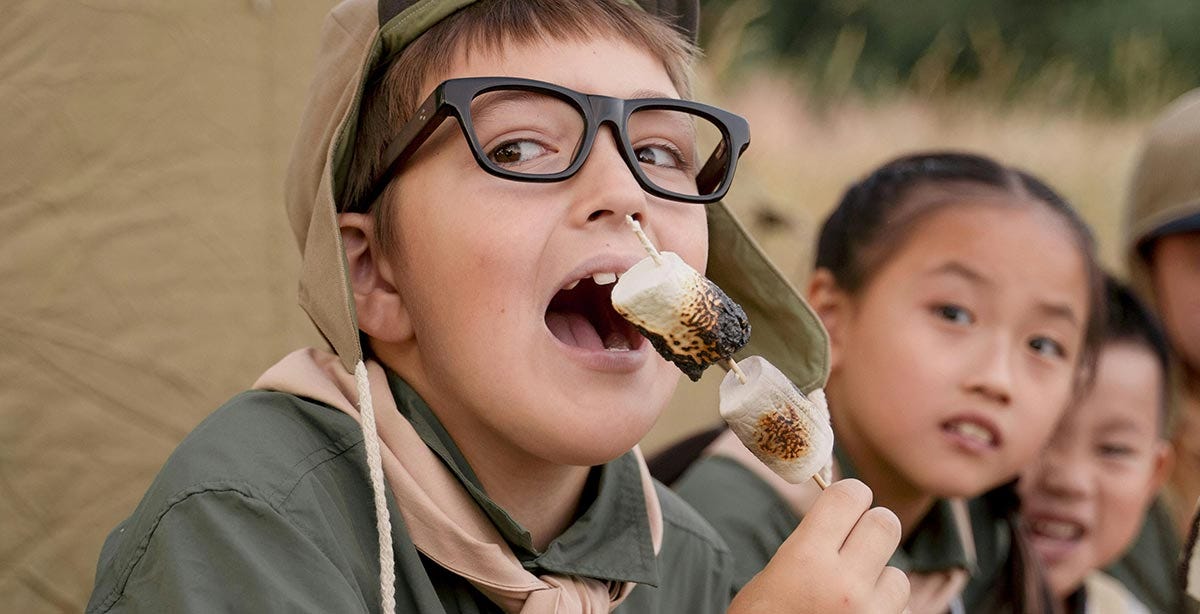 Kids camping and eating marshmallows.