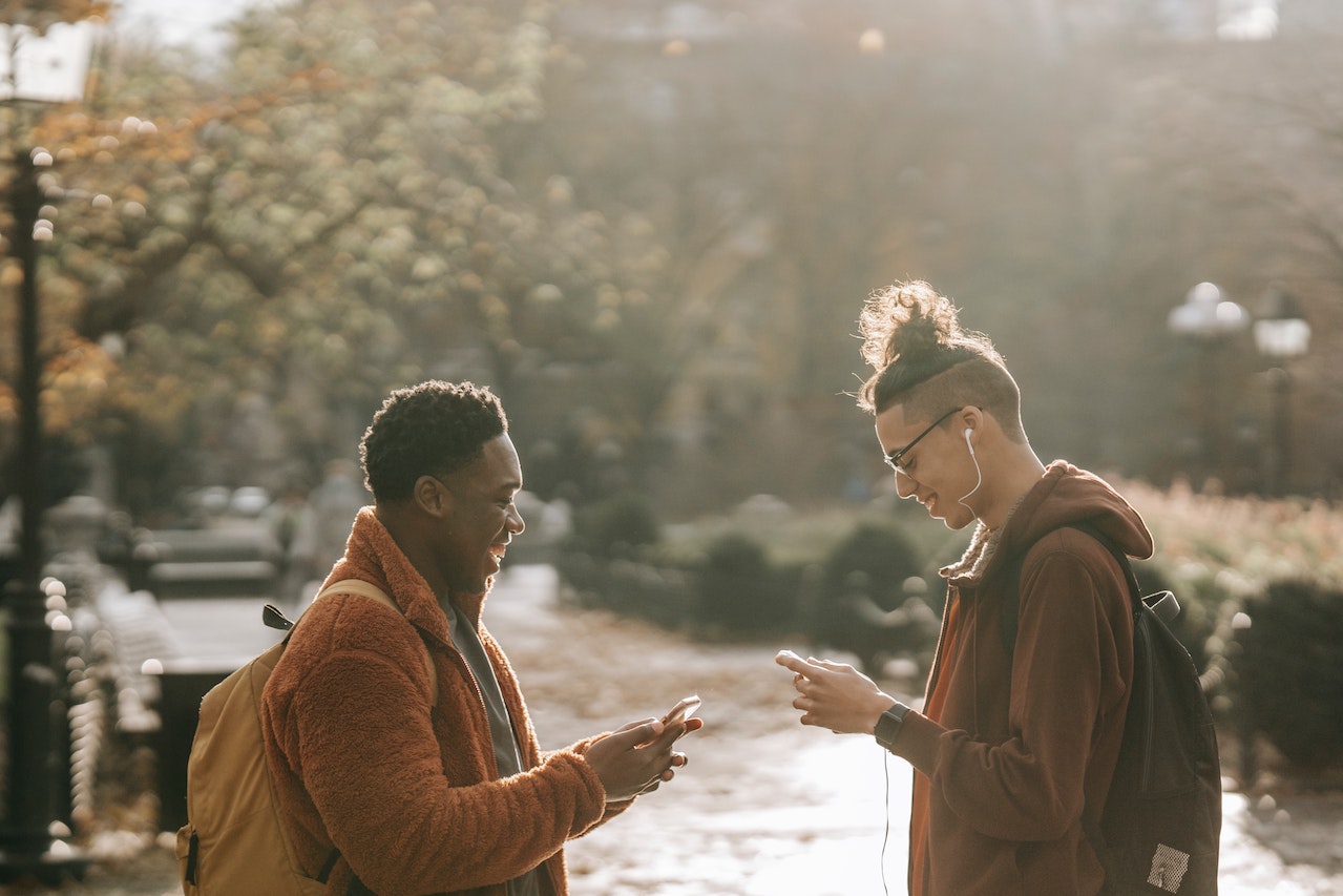 Two friends laughing in a park over Spanish texting abbreviations