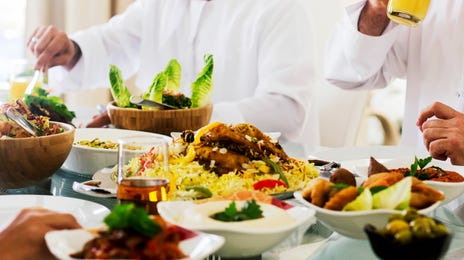 A group of men wearing traditional Middle Eastern attire sharing a meal together, representing cultural immersion and a community-driven way to learn Arabic online.