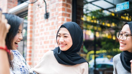 A group of young women chatting and smiling at a coffee shop, demonstrating a friendly and relaxed environment for Indonesian language lessons.