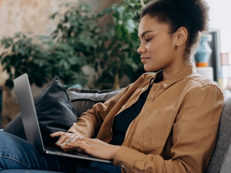 Woman with a laptop in her lap reading about the future continuous tense