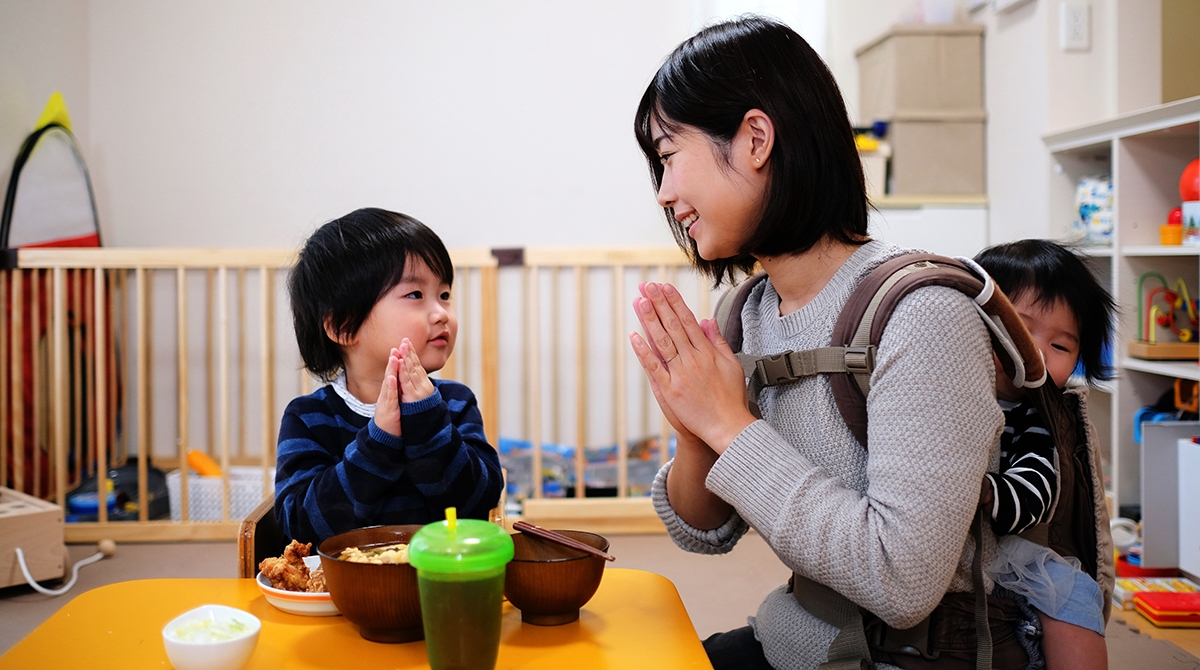 Culture influences language as a mother and son pray before their meal.