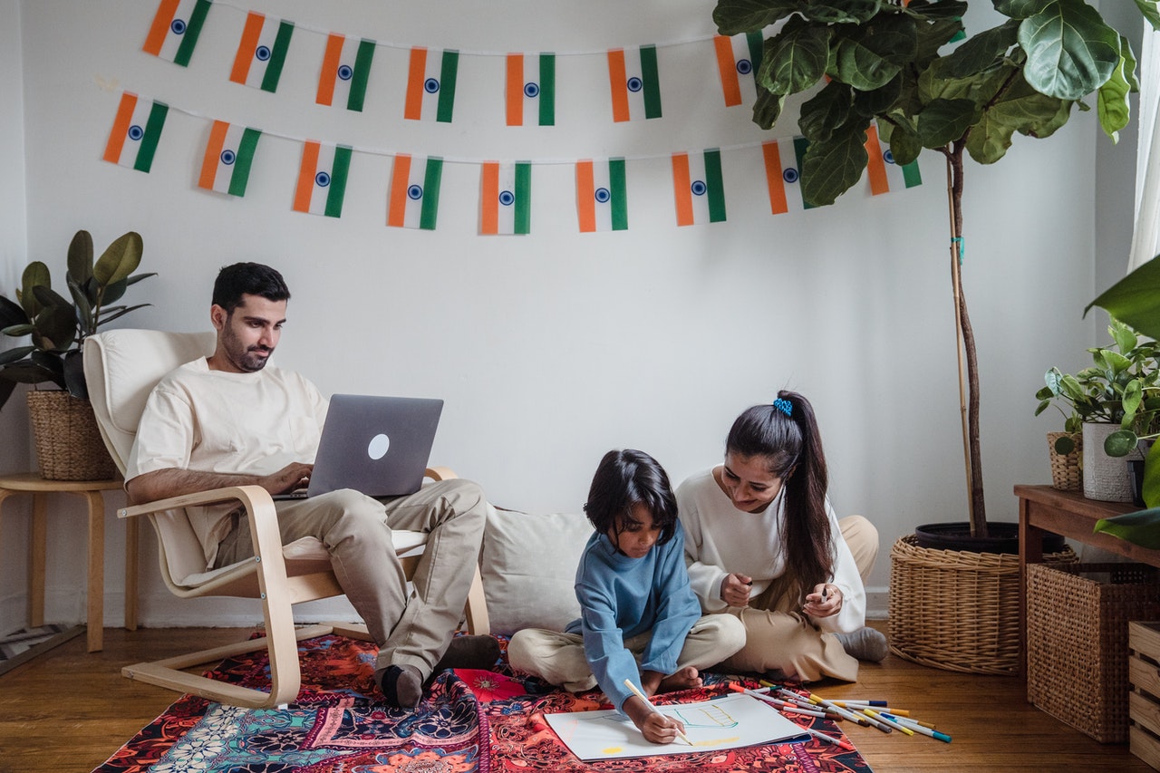 Happy mum and dad teaching child about Indian languages spoken in India with Indian flag background