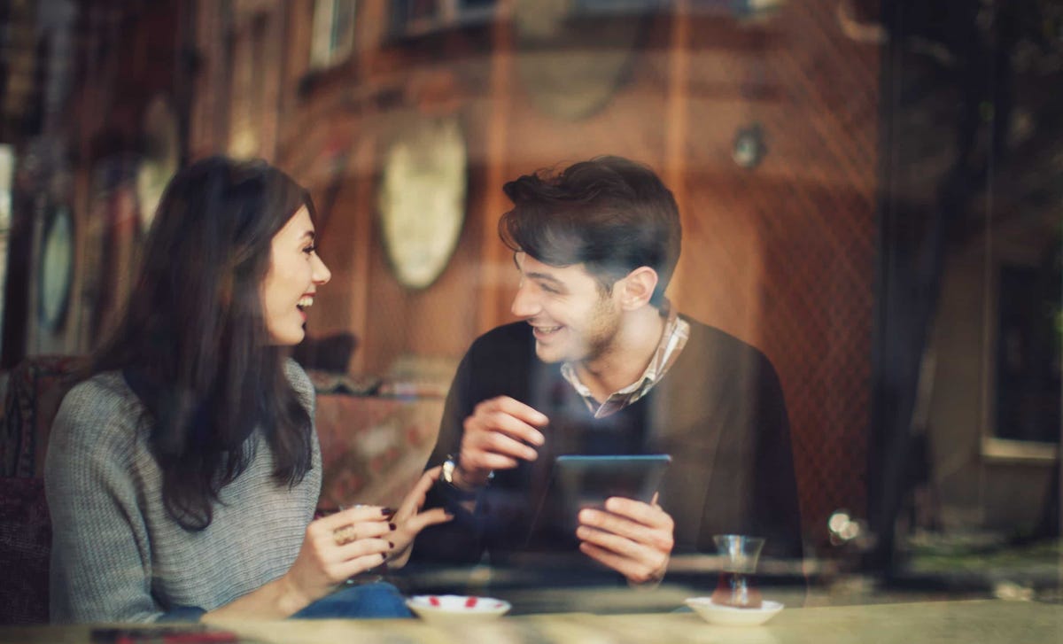 Man and woman enjoying a lively conversation at a café, illustrating real-life fluency through the immersive Berlitz Method.