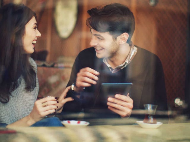 Man and woman enjoying a lively conversation at a café, illustrating real-life fluency through the immersive Berlitz Method.