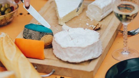 A delightful spread of cheeses, bread, and wine being enjoyed during an online Italian group class, with people sharing and tasting different foods.
