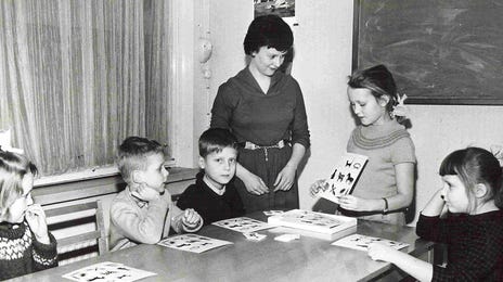 Vintage classroom scene showing a Berlitz language lesson for kids using visual aids and flashcards.