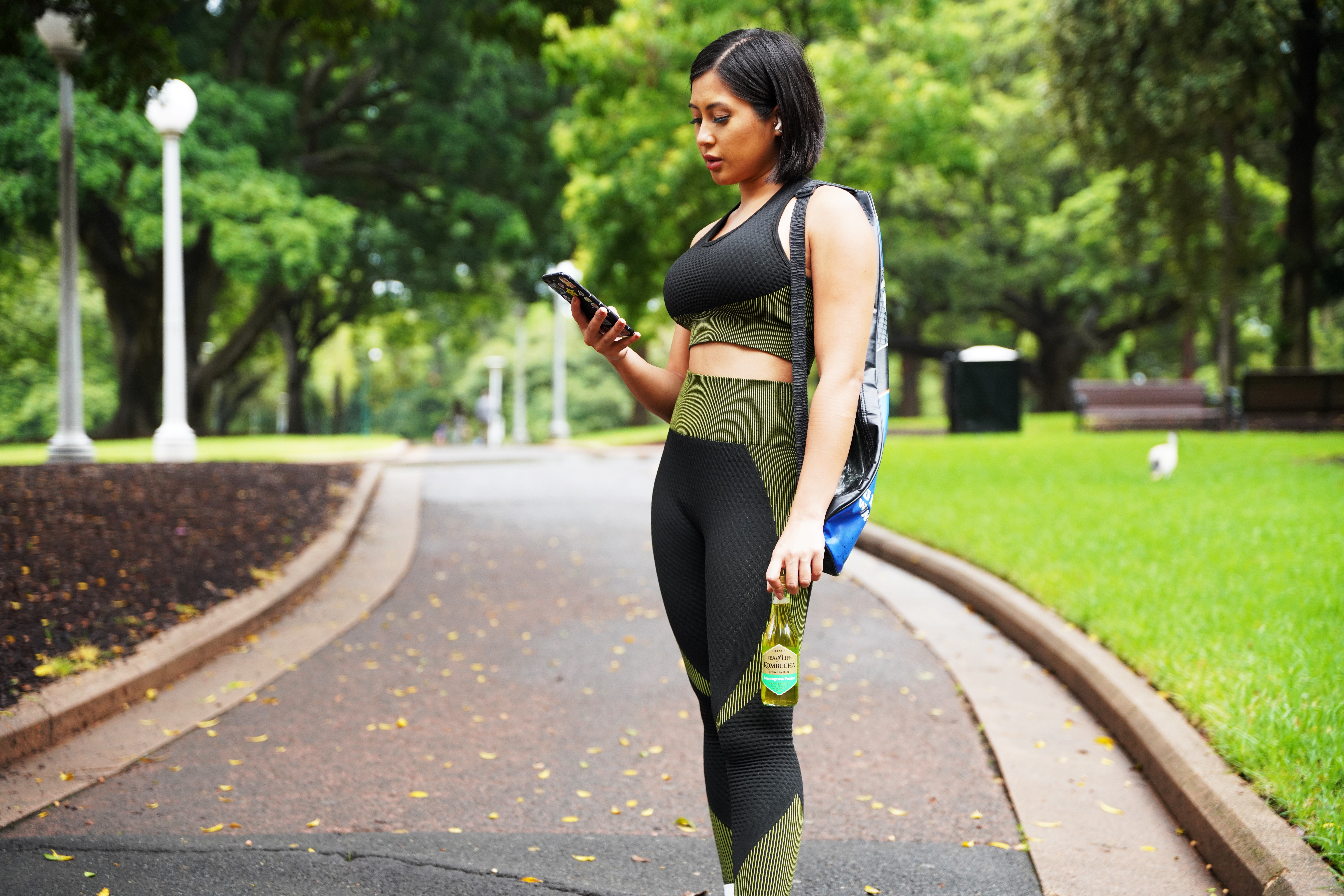 Woman in activewear looking at phone during a walk, possibly reviewing advanced English courses online