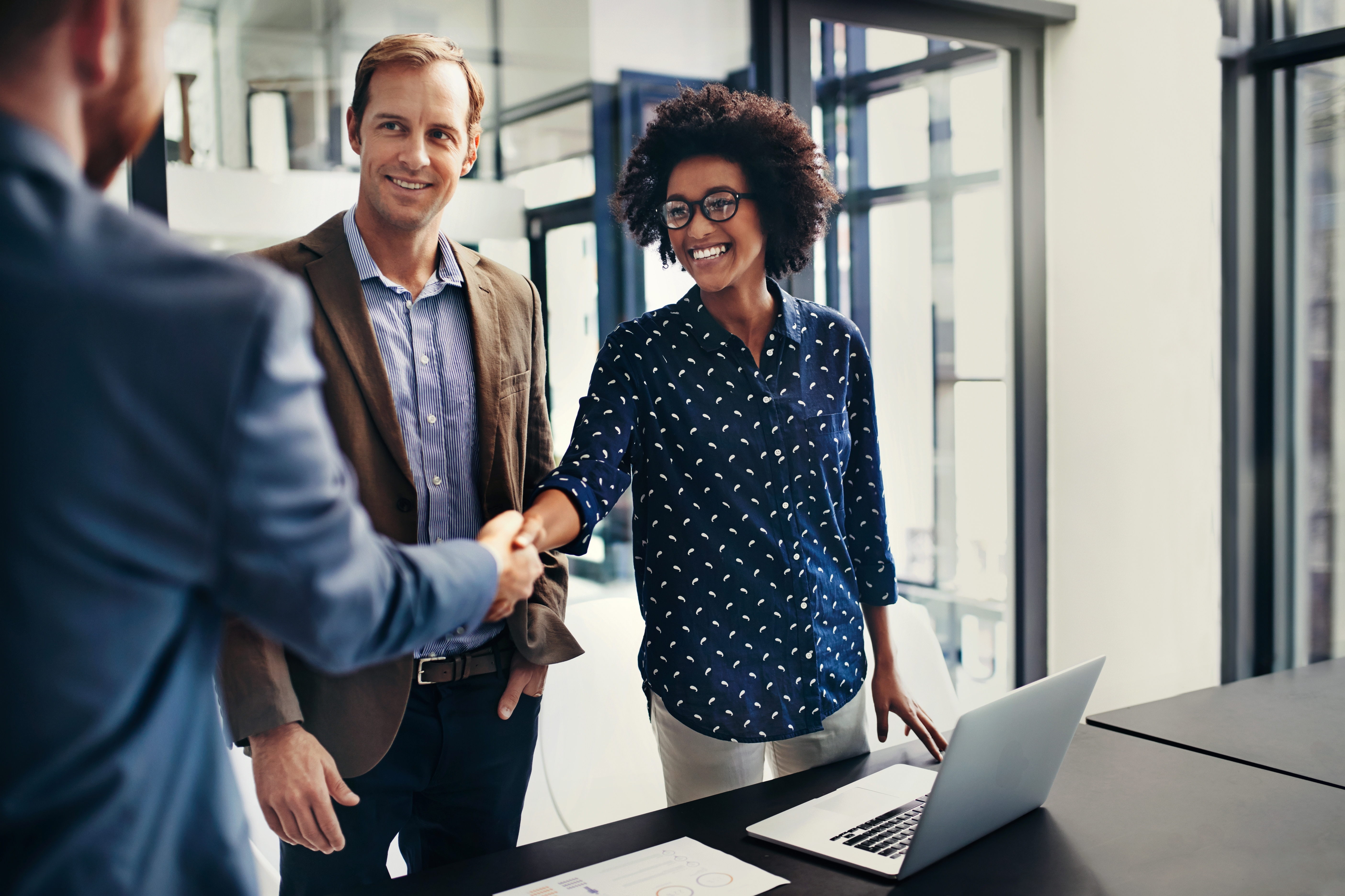 Business professionals shaking hands in an office, highlighting Berlitz’s corporate language training programs for professional communication success.

