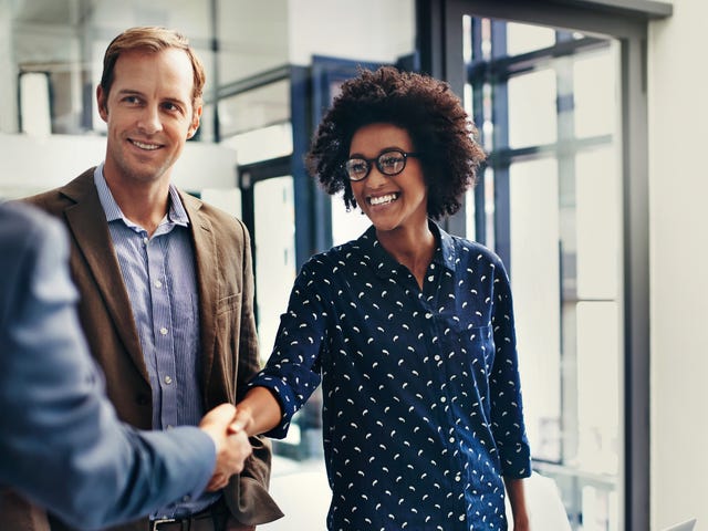 Business professionals shaking hands in an office, highlighting Berlitz’s corporate language training programs for professional communication success.