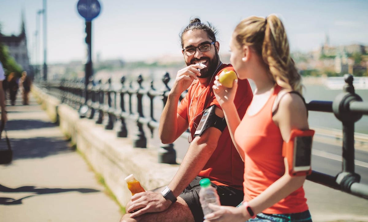 Two active young adults in workout gear enjoying a break outdoors, symbolizing flexibility and lifestyle balance with online German classes.