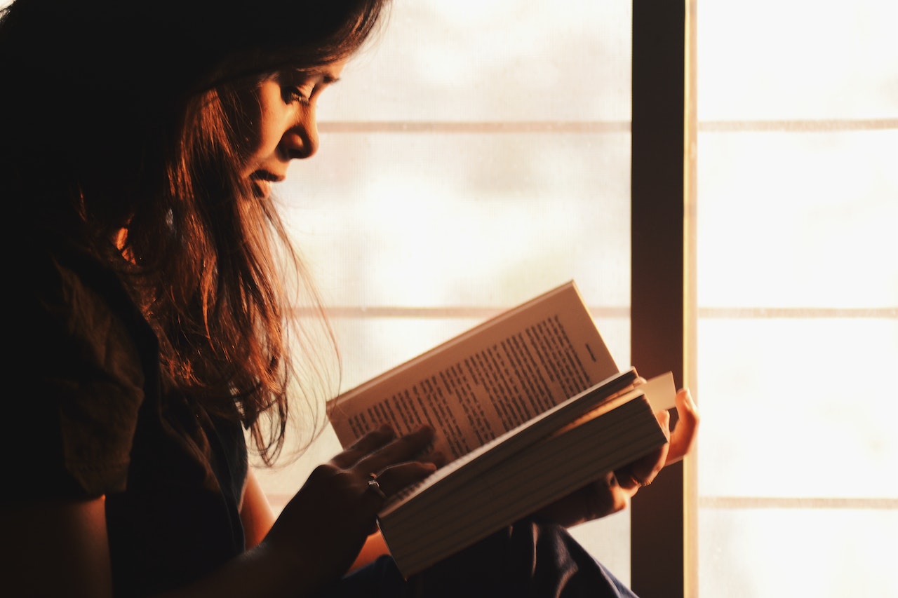 Woman is reading a book that contains the hardest English words to spell and pronounce.