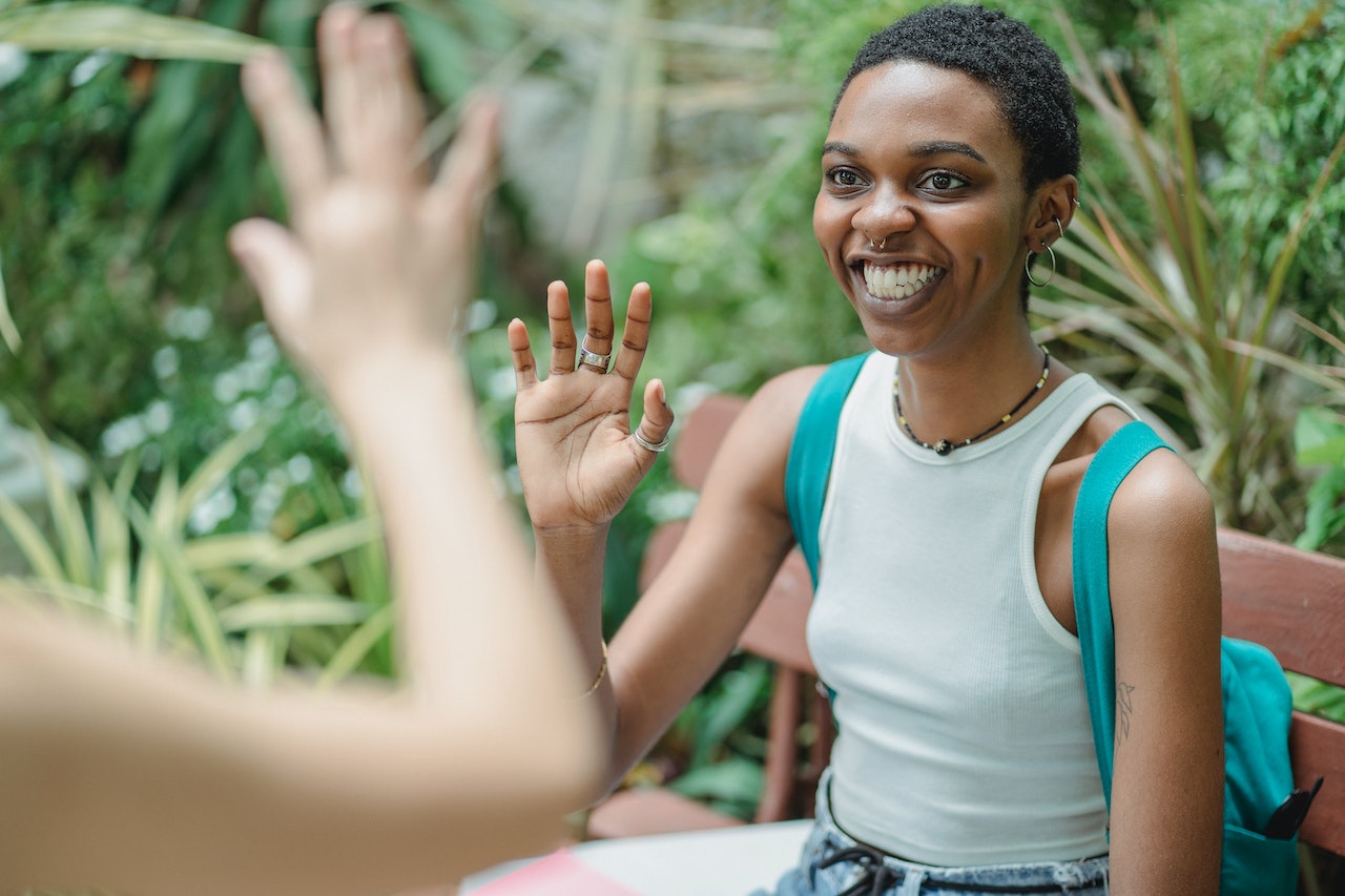 Smiling woman waving to friend how to say good afternoon in Italian.