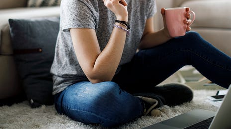 Focused woman studying with a laptop and notes, participating in online French group classes from home