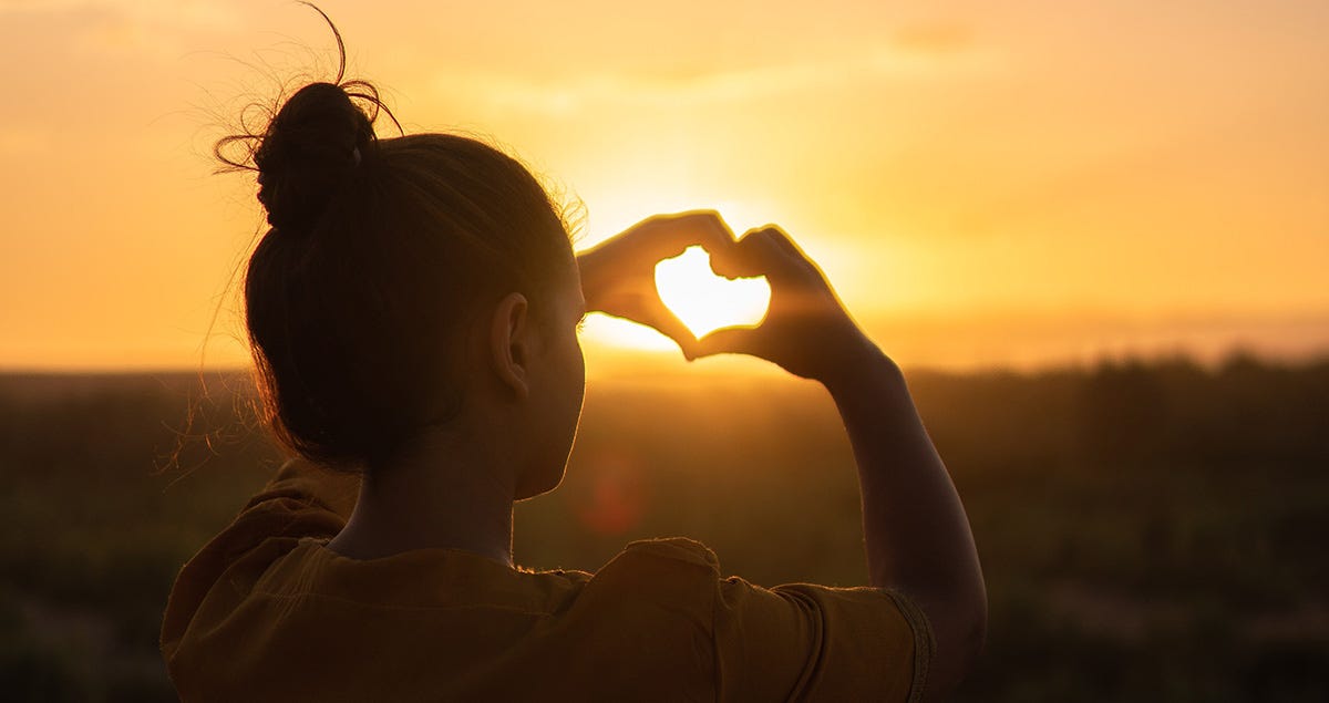 Woman makes heart shape with hands to say I love you in French.