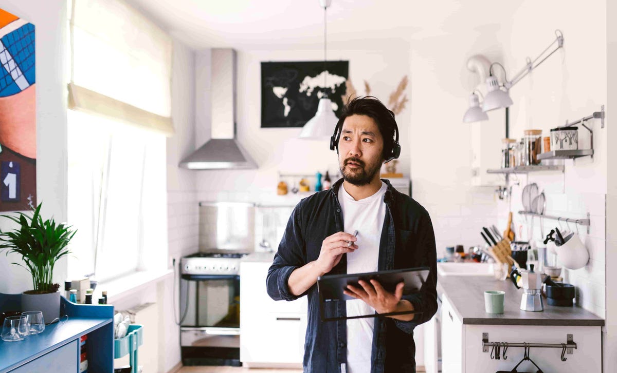 Man wearing a headset while teaching from his kitchen using a tablet, representing the flexibility of Berlitz Spanish courses taught online.