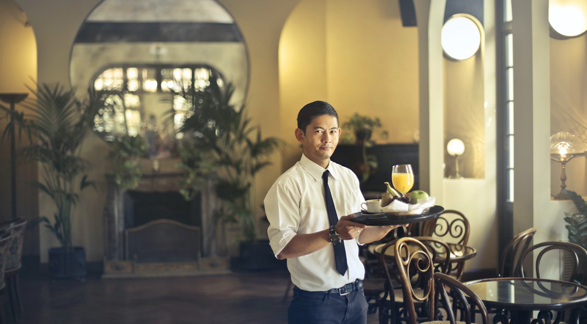 A waiter serving drinks and snacks for customers who ordered food in French.